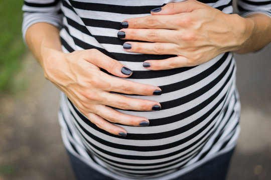 Hands on the belly of the pregnant woman