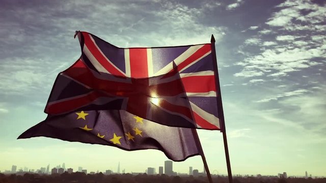 European Union and British Union Jack flag flying together in front of a sunrise skyline of London, England