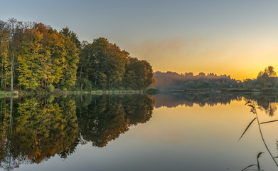 Fototapeta na wymiar Colorful sunset in autumnal forestry lake, Europe