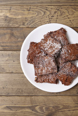 A plate full of freshly baked chocolate fudge brownies on a rustic wooden table background