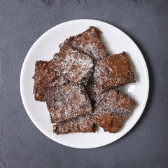 Aerial view of a plate full of freshly baked chocolate fudge brownies on a rustic slate background