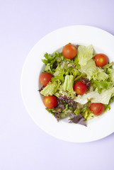 A dish of classic side salad on a pastel purple background