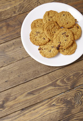 A plate full of freshly baked oatmeal and raisin cookies on a rustic wooden background with a blank space below
