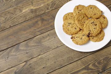 A plate full of freshly baked oatmeal and raisin cookies on a rustic wooden background with a blank space at side