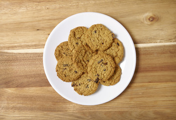 A plate full of freshly baked oatmeal and raisin cookies on a wooden kitchen counter background
