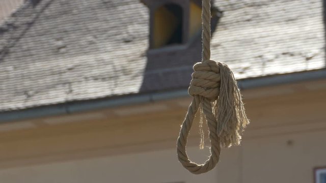 Close up shot of a hanging rope swinging gently in the air.
