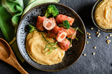 Roasted pork cutlets wrapped in bacon and stuffed with sausage, served with peas puree