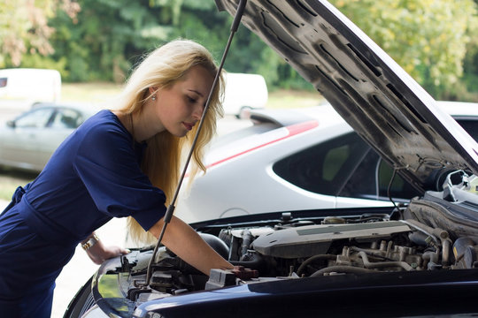 Woman Reparing The Car Under The Hood