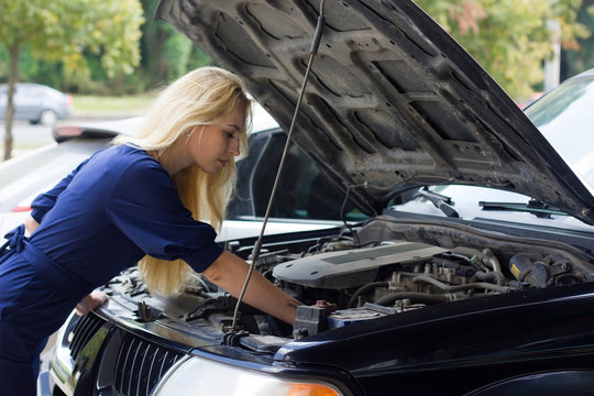 woman reparing the car under the hood