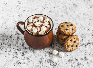 Hot chocolate with marshmallows and chocolate chips oatmeal cookies on a light background.