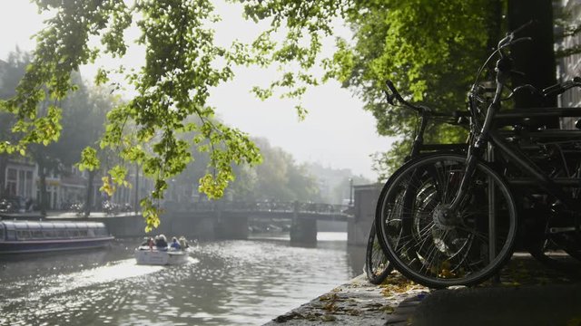 View of wheel of bicycle on the Amsterdam amstel canal, next to floats tour boat, sunny european autumn