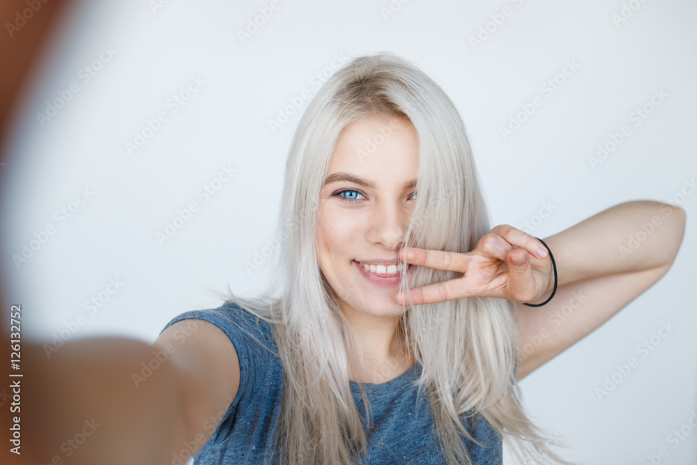 Wall mural smiling young girl making selfie photo