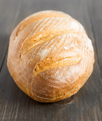 Loaf of homemade bread on wooden rustic table.