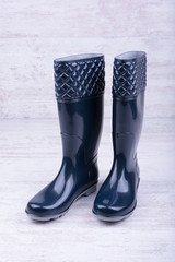 Pair of blue rubber boots on white wooden background