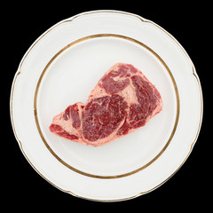 Raw rib-eye steak on plate, isolated