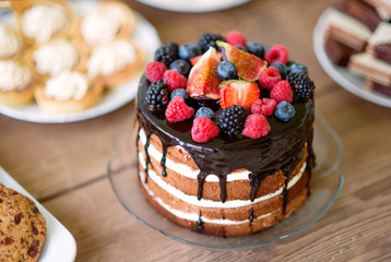 Naked cake with chocolate and berries, cookies and tarts