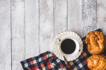 Top view of Coffee cup with bread and tablecloth on wooden table