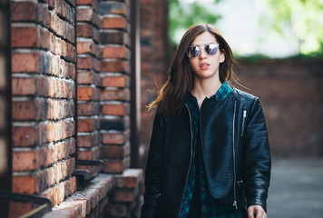 Urban fashionable girl posing in a leather jacket outdoors in the city