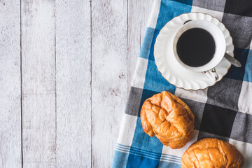 Top view of Coffee cup with bread and tablecloth on wooden table