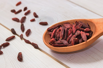 Goji berries in a wooden spoon on a white background. Healthy eating.