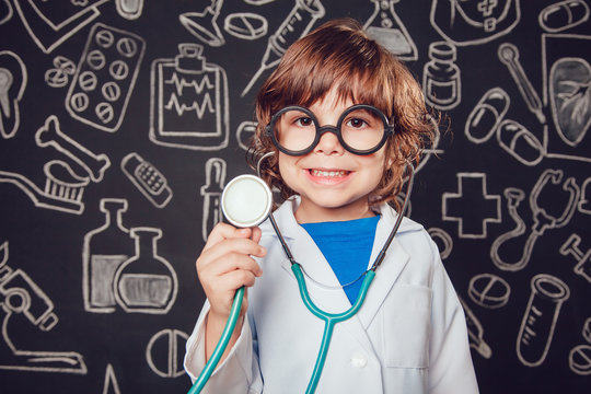 Happy Little Boy In Doctor Costume Holding Sthetoscope On Dark Background With Pattern. The Child Has Glasses