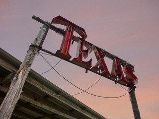 Texas neon sign against evening sky with rustic wood