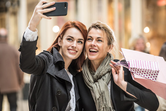 in the city, two beautiful women take a selfie with a phone