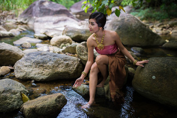 Beautiful girl with Thai dressing was playing water in the river.
