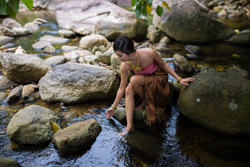 Beautiful girl with Thai dressing was playing water in the river.