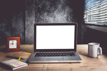 Fototapeta premium Laptop with white blank screen on wooden desk