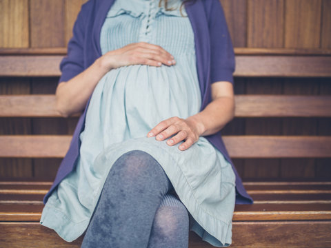Pregnant woman sitting on bench in shelter