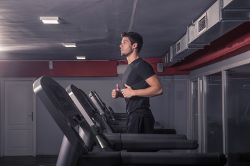 young man running treadmill, indoors gym.