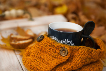 Warm cup of coffee with scarf and cookies on wooden table background on autumn time