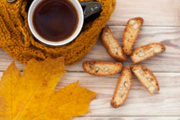 Warm cup of coffee with scarf and cookies on wooden table background on autumn time