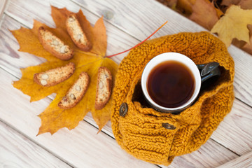 Warm cup of coffee with scarf and cookies on wooden table background on autumn time