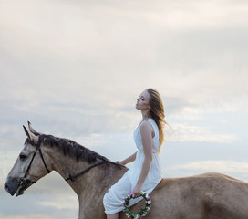 Sensual blond woman riding a brown stallion
