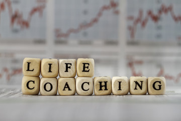 Life coaching word built with letter cubes on newspaper background