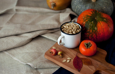 Autumn composition: persimmon, pumpkin, pumpkin seeds with autumn leaves