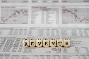 Revenue built with letter cubes on newspaper background