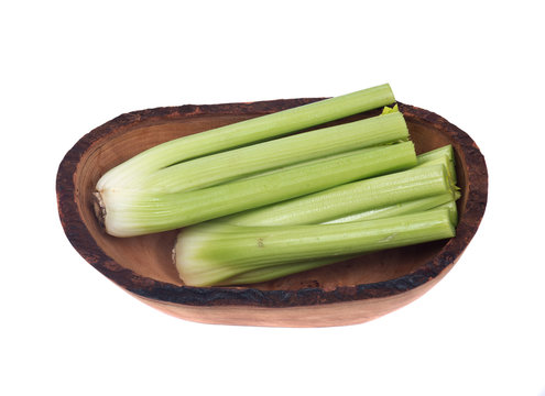 Fresh organic celery in olive wood bowl isolated on white background