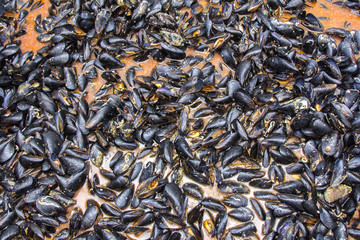 Mussels in red sauce in big cauldron on a Street market