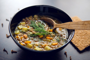lentil soup in a black bowl on dark wooden table