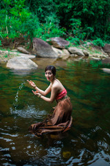 Fototapeta premium Beautiful girl with Thai dressing was playing water in the river.