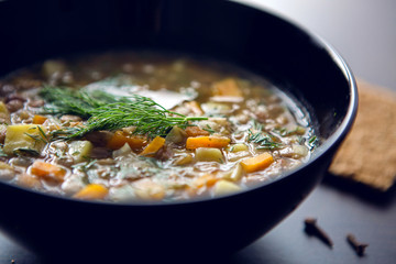 lentil soup in a black bowl on dark wooden table
