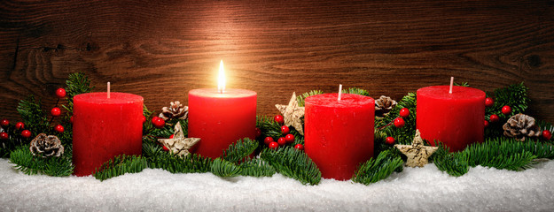 Advent Dekoration mit einer Kerzenflamme, Schnee, Tannenzweigen und Holz Hintergrund