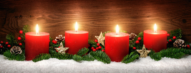 Advent Dekoration mit vier Kerzenflammen, Schnee, Tannenzweigen und Holz Hintergrund