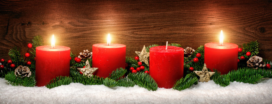 Advent Dekoration mit drei Kerzenflammen, Schnee, Tannenzweigen und Holz Hintergrund