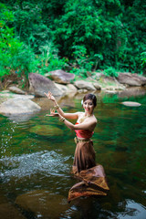 Beautiful girl with Thai dressing was playing water in the river.