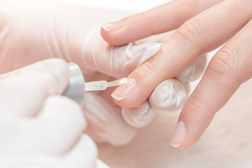 beautician applying Polish nails to women 
