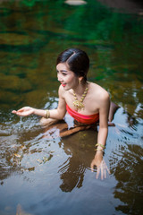 Fototapeta premium Beautiful girl with Thai dressing was playing water in the river.